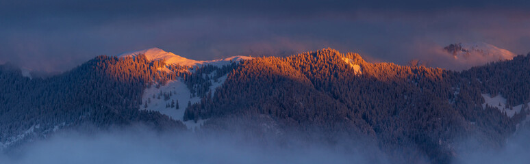 Colorful winter sunset panorama  in the Alps, above the inversion and clouds