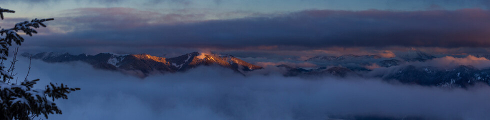Colorful winter sunset panorama  in the Alps, above the inversion and clouds
