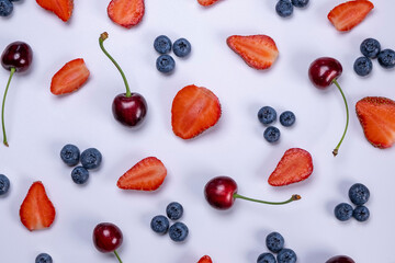 background of blueberries, strawberries, lemon, orange, grapefruit and kiwi slices on a white background - the concept of a healthy diet. Summer bright food fruit background, food design