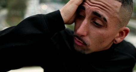 Troubled hispanic man feeling anxious in city, person suffering in pain