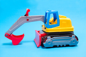 Yellow excavator plastic car on blue background. Construction machinery car for digging for toy store and children.