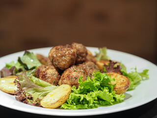Dish of meatballs with potatoes and salad