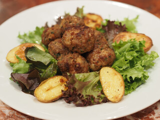 Dish of meatballs with potatoes and salad