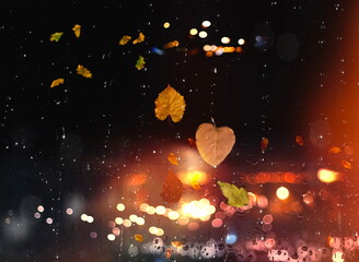 Autumn leaves on window rain drops and Autumn leaves fall night city traffic blurred light colorful...