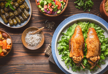 Arabic Cuisine; Egyptian traditional stuffed pigeon or "Hamam Mahshi" dish. Served with green salad, oriental pickles, cooked Freekeh and stuffed vine leaves. Close up with copy space.
