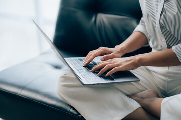 Happy young asian businesswoman sitting on her workplace in the office. Young woman working at laptop in the office