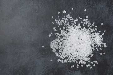 Sea salt in wooden bowl on black table.