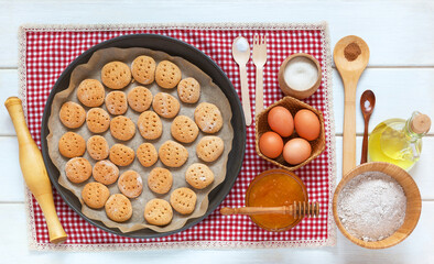 The process of making homemade honey cinnamon cookies from rye flour, eggs, vegetable oil, honey and spices on a kitchen wooden table. Healthy home food. Top view, close-up, flat lay