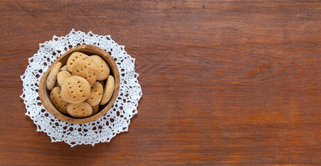 Freshly baked homemade cinnamon gingerbread cookies in a wooden bowl on a lace napkin on a wooden table. Festive meal. Free space for recipe text. Top view, close-up, flat lay, mock up, copy space