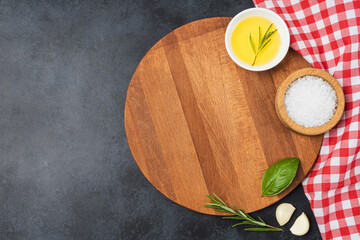 Wooden cutting board and spices on black stone table. Top view