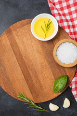 Wooden cutting board and spices, herb for food on black stone table