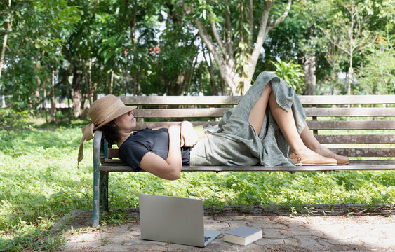 Woman laying down on old bench in a park,for relax time ,