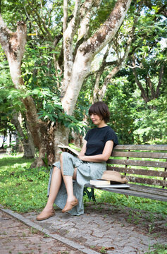 Woman sitting on old bench,reading book,hobby on holiday