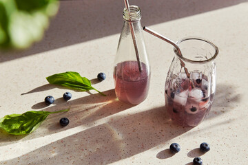 Natural herbal organic drink with blueberries, basil extract, ice under hard shadows. Refreshing...
