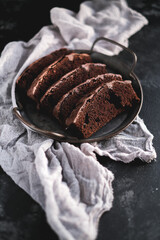 Homemade chocolate cake on dark background. Tasty brownies on plate. Double chocolate pastry. Delicious vegetarian dessert. Gluten free bakery. Selective focus. 