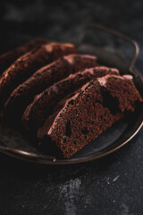 Homemade chocolate cake on dark background. Tasty brownies on plate. Double chocolate pastry. Delicious vegetarian dessert. Gluten free bakery. Selective focus. 