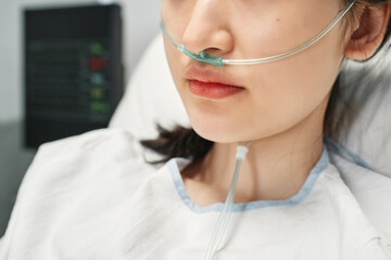 Close-up shot of young Asian woman wearing nasal cannula spending day in emergency room after accident - obrazy, fototapety, plakaty