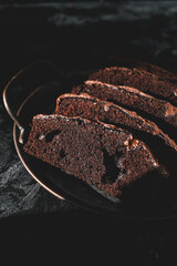 Homemade chocolate cake on dark background. Tasty brownies on plate. Double chocolate pastry. Delicious vegetarian dessert. Gluten free bakery. Selective focus. 