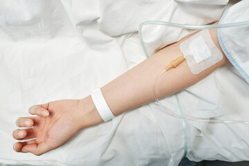 From above view shot of unrecognizable female patient receiving medication fluids through IV line