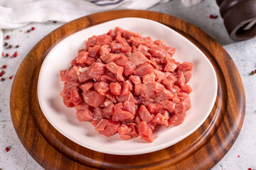 Cubed meat. Red meat in a chopped plate on a stone floor. Butcher products. close up