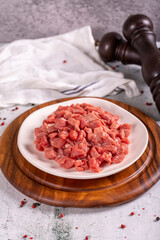 Cubed meat. Red meat in a chopped plate on a stone floor. Butcher products. close up