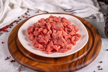 Cubed meat. Red meat in a chopped plate on a stone floor. Butcher products. close up