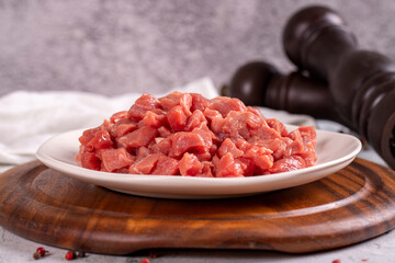 Cubed meat. Red meat in a chopped plate on a stone floor. Butcher products. close up