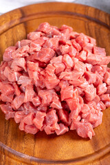 Cubed meat. Chopped red meat in a wooden serving dish on a stone background. Butcher products. close up
