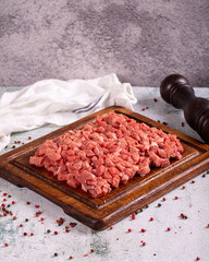 Cubed meat. Chopped red meat in a wooden serving dish on a stone background. Butcher products. close up