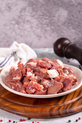 Lamb cubed meat. Chopped red meat in a plate on a stone floor. Butcher products. close up