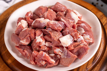 Lamb cubed meat. Chopped red meat in a plate on a stone floor. Butcher products. close up