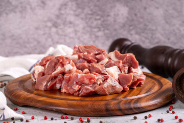 Lamb cubed meat. Chopped red meat in a wooden serving dish on a stone background. Butcher products. close up
