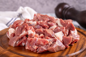 Lamb cubed meat. Chopped red meat in a wooden serving dish on a stone background. Butcher products....