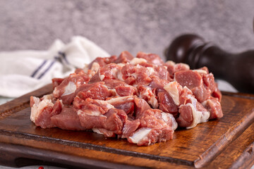 Lamb cubed meat. Chopped red meat in a wooden serving dish on a stone background. Butcher products. close up
