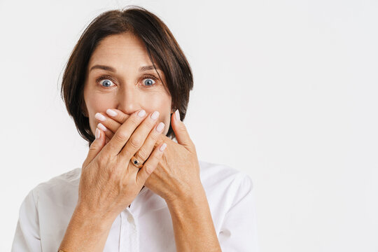 Mature brunette woman expressing surprise while covering her mouth