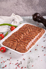Packaged uncooked spicy grilled meatballs. Meatballs on stone background. close up