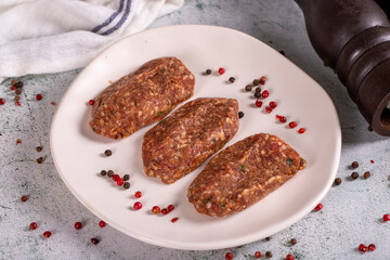 Uncooked spicy grilled meatballs. Meatballs in a plate on a stone background. close up