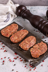 Uncooked spicy grilled meatballs. Meatballs on a stone serving plate on a stone background. close up