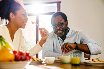 African american woman and man sitting by table while having breakfast