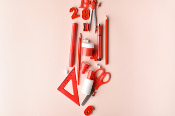 Various office supplies of red color lie in the center on a beige background. Back to school. A banner with office elements with space for text. Space for copying. Flat position, top view