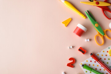 Various stationery of red, yellow and green colors are in the center on a beige background. Back to school. Space for copying. Flat position, top view