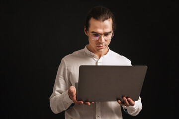 Adult long-haired man in glasses and shirt holding laptop