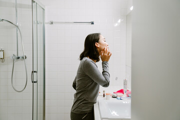 Fototapeta na wymiar Young calm asian girl preening in front of a mirror
