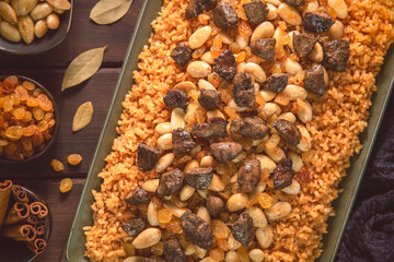 Arabic Cuisine: Traditional rice with chicken liver dish. A delicious plate of rice topped with crispy nuts, raisins and small pieces of chicken liver and hearts. Top view with close up.