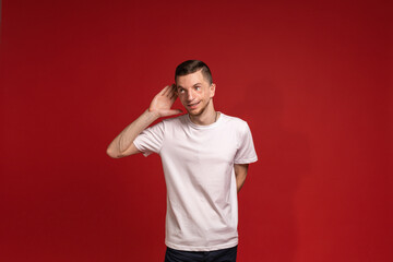 A young man in a white T-shirt listens