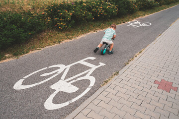 Boy on a bike. Child on balance bike riding on a bike path. Concept of healthy lifestyle, childhood