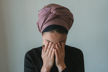 Young jewish woman with a covered head prays, covering her eyes with her hands (65)