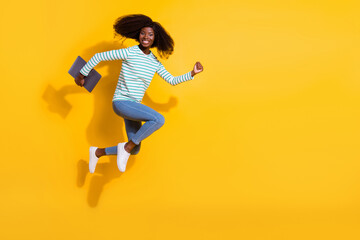 Fototapeta na wymiar Full size profile photo of energetic excited person hold netbook hurry jump run empty space isolated on yellow color background