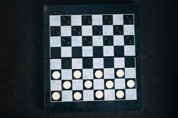 Checkers board with chips black background, checkers logical board game.