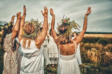 Women in flower wreath on sunny meadow, Floral crown, symbol of summer solstice. - obrazy, fototapety, plakaty